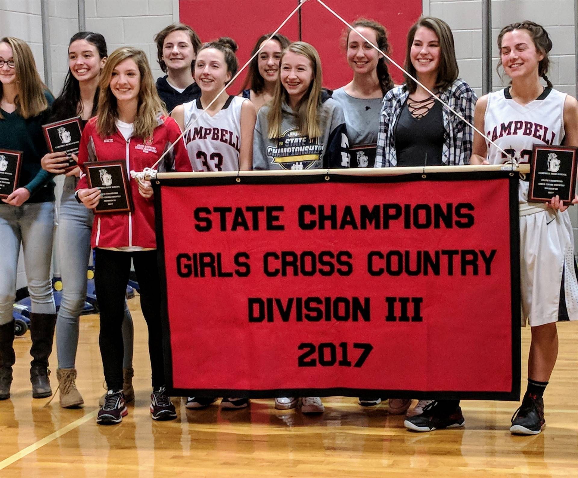 Raising the Girls Cross Country 2017 State Champion banner